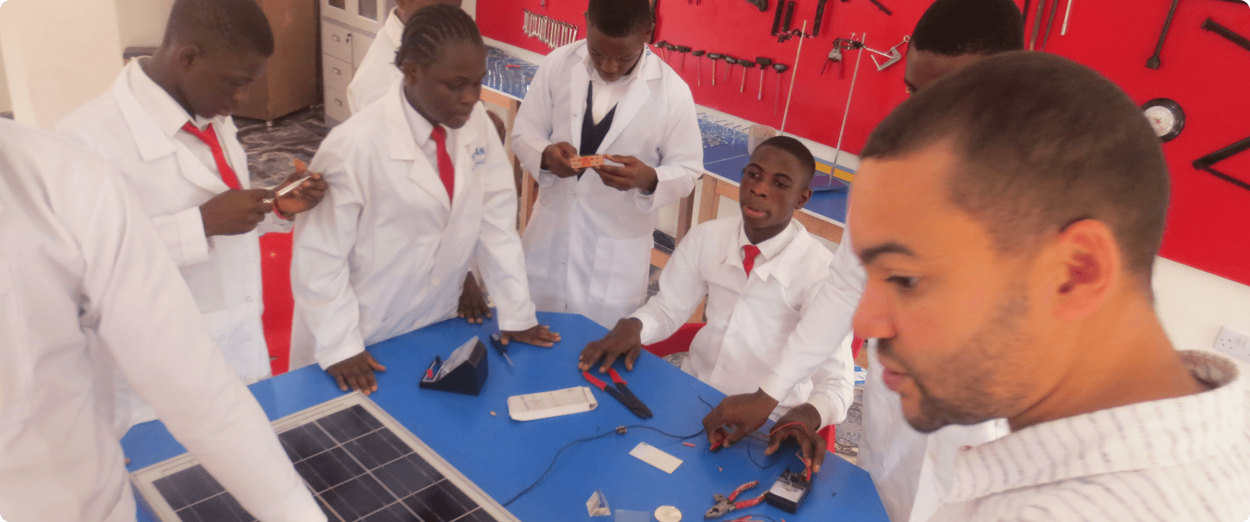 Schüler in weißen Laborkitteln arbeiten mit Solarpanelen in einer Unterrichtsumgebung